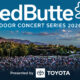 Outdoor concert scene for RedButte Outdoor Concert Series 2026 with a large audience and a stage set against hills at dusk, Presented by Toyota